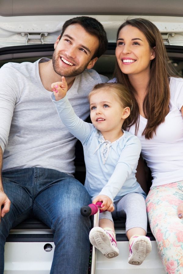 family sitting in trunk of car