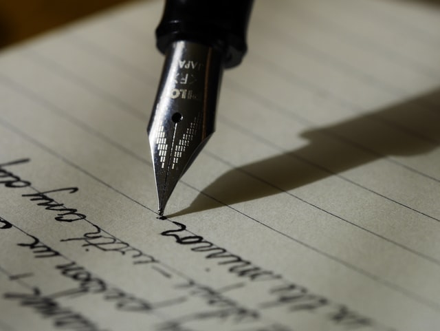 A student writing an essay with a pen.