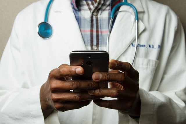 A medical representative wearing a stethoscope and holding a phone.