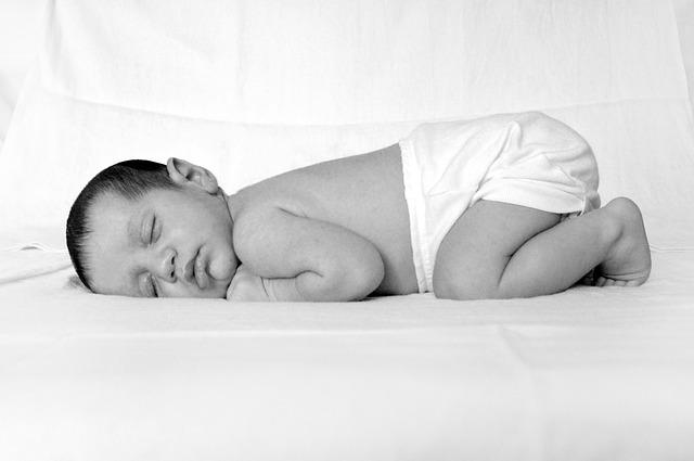 A baby calmly sleeping, wearing a cloth diaper.