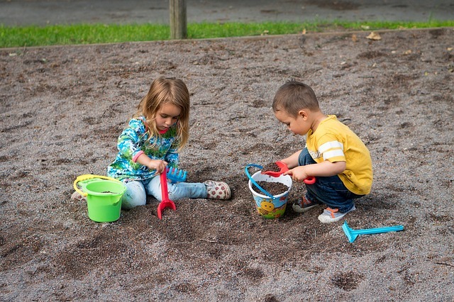 Kids playing on the beach with sand, spade and buckets.