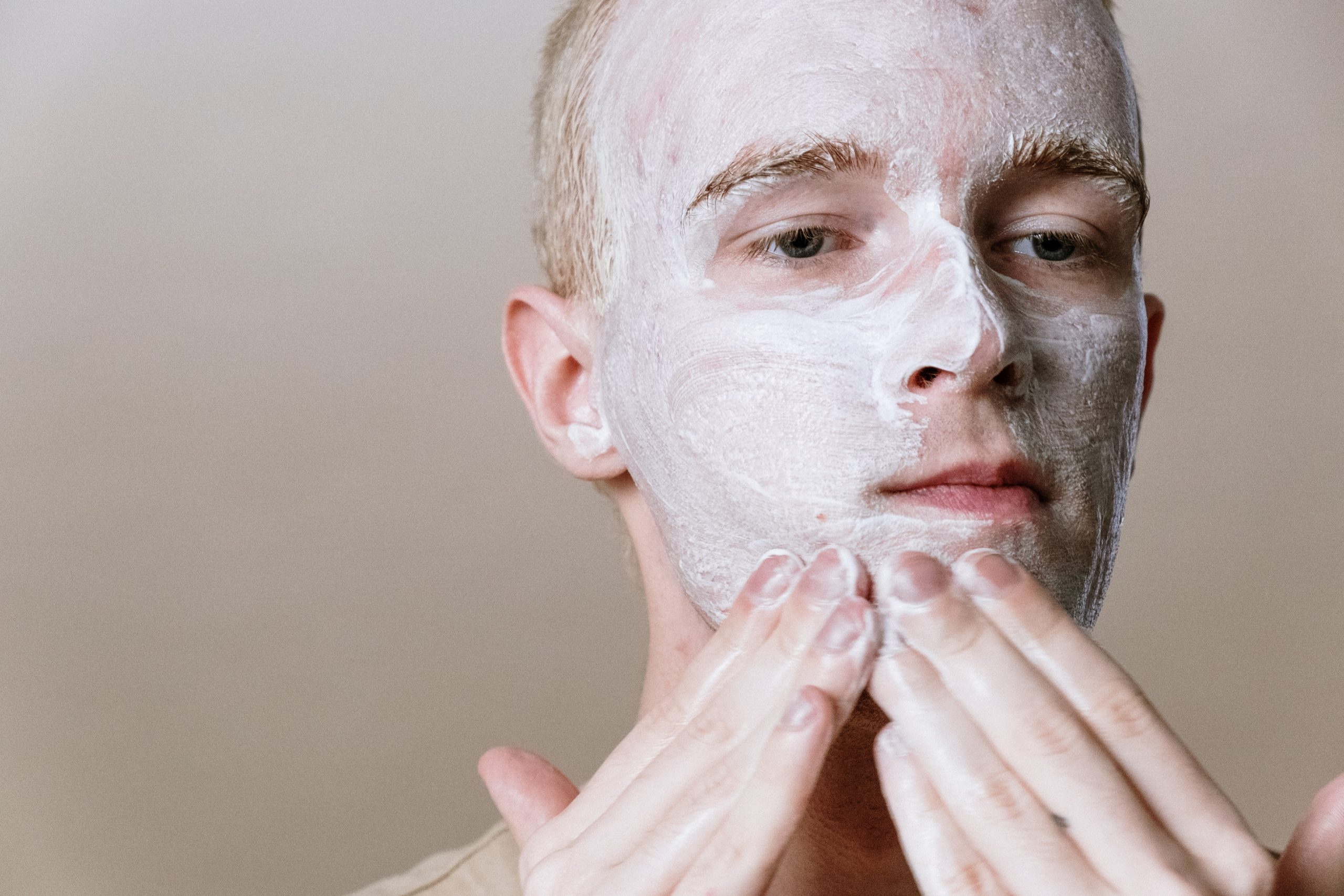 A man applying cleansing balm on his face.