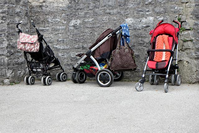 Three umbrella strollers in different colors were parked.