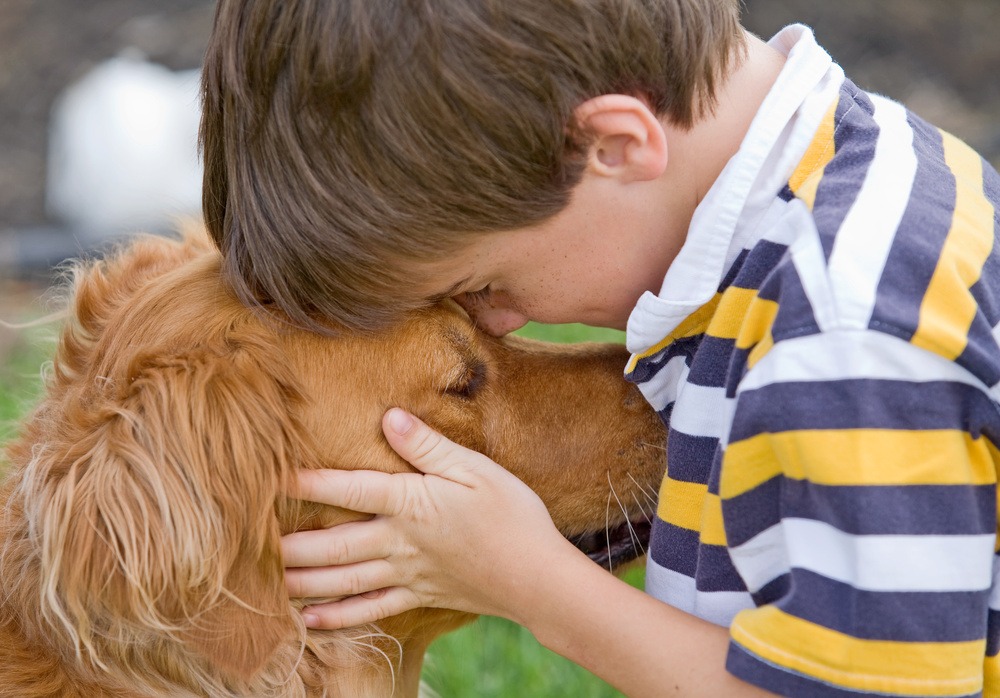 A boy cuddling with his dog.