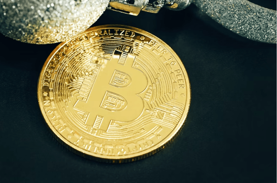 A golden bitcoin is placed on a table.