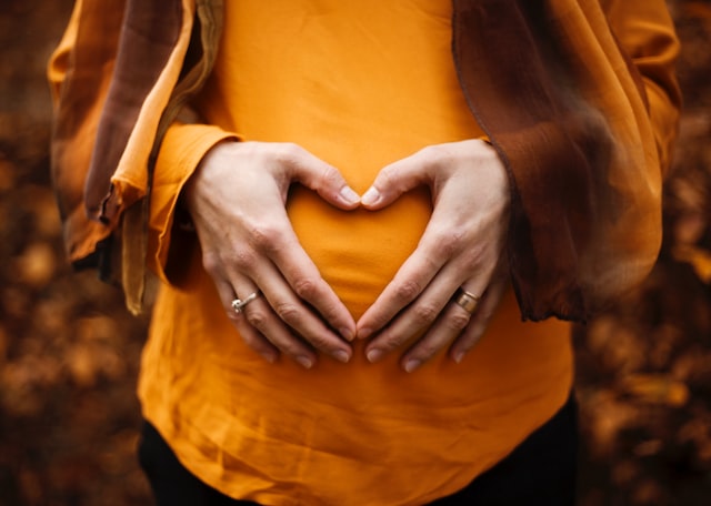 A pregnant woman displaying a heart on her tummy.