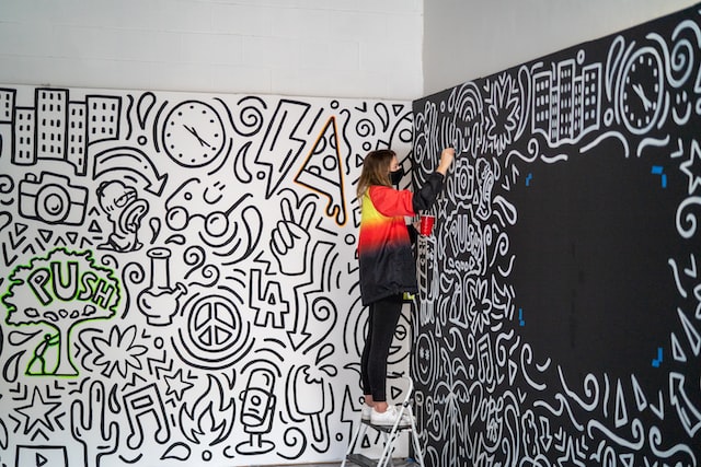 A woman artistically painting the wall/