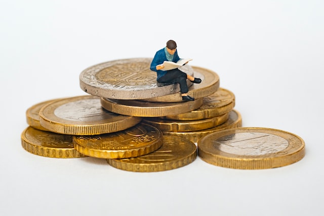 A man reading a book sitting on coins.