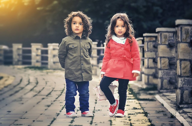 Two small girls walking on the road.