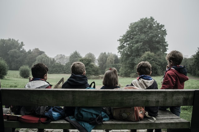 a group of kids sitting om a bench.