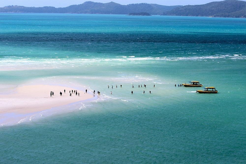 Tour boats anchored near Whitehaven Beach as visitors explore the crystal-clear shallows and white silica sands of the Whitsundays.