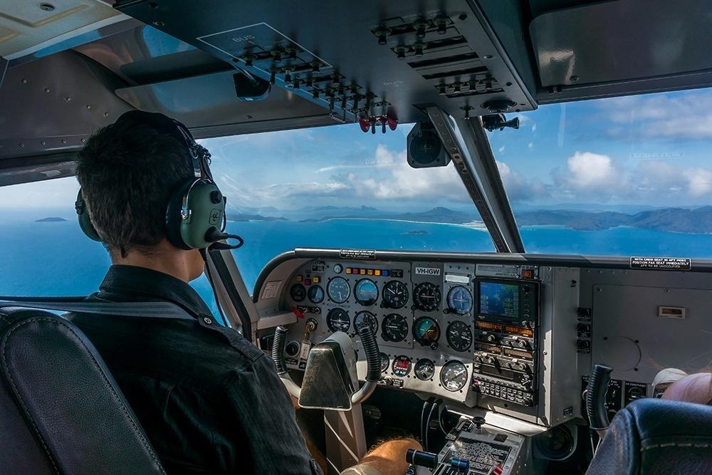 Cockpit view of a scenic flight over the Whitsunday Islands, revealing the region’s vibrant blue waters and island scenery.